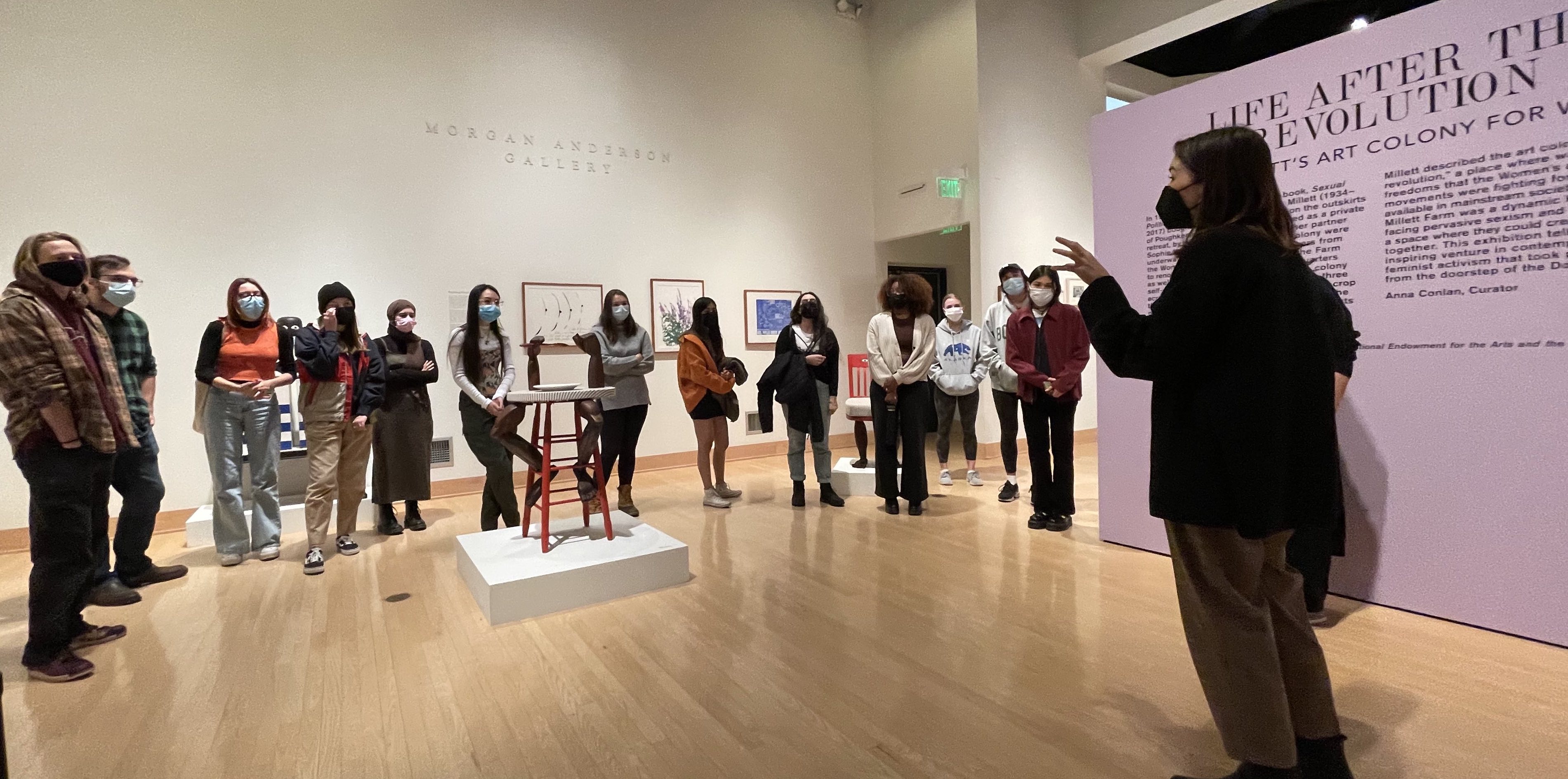 Woman talking to a circle of students in the gallery